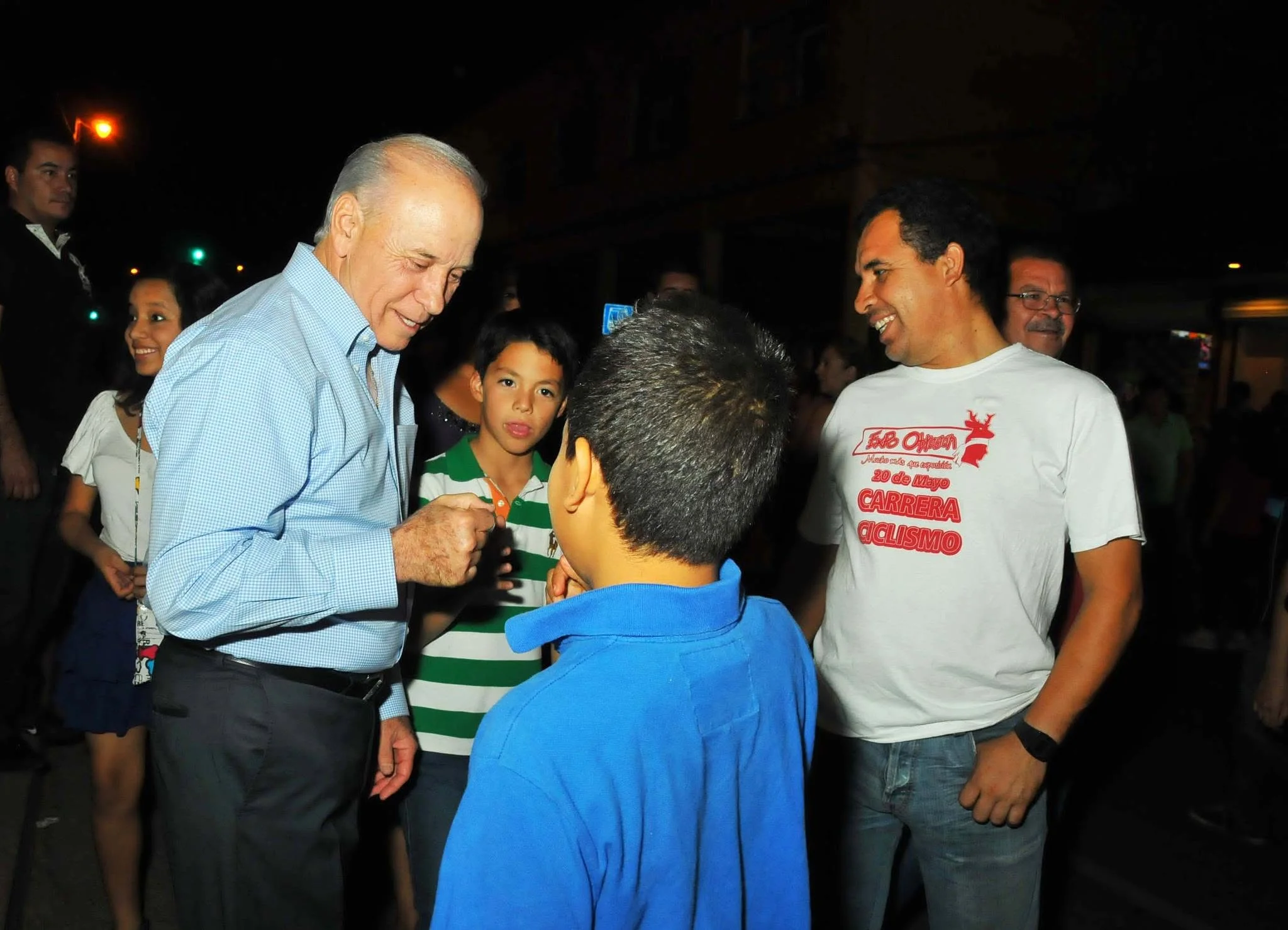 Javier Gándara Magaña saludando de puño a un joven mientras sonríe