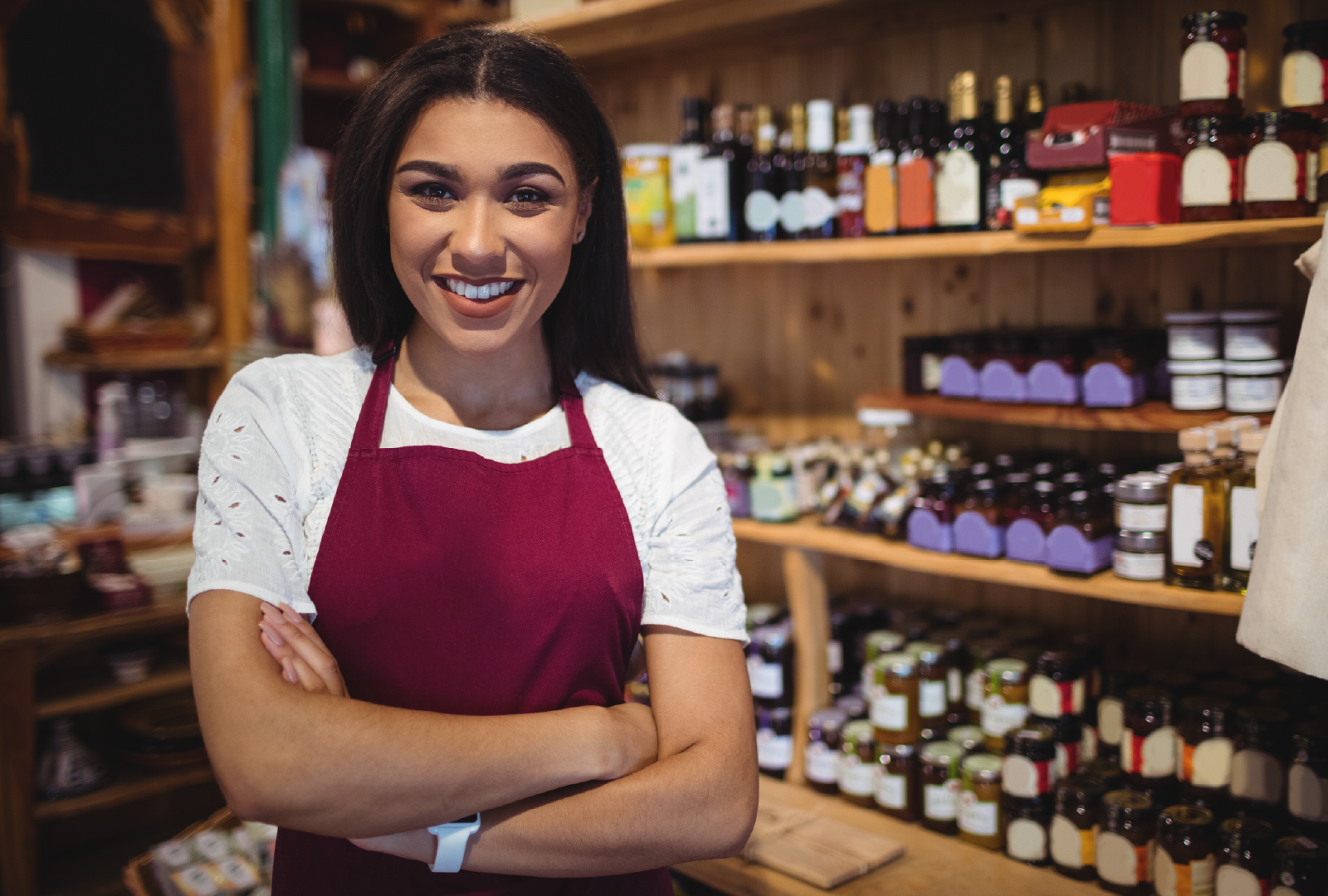 Mujer sonriente con delantal en una tienda de productos gourmet y conservas